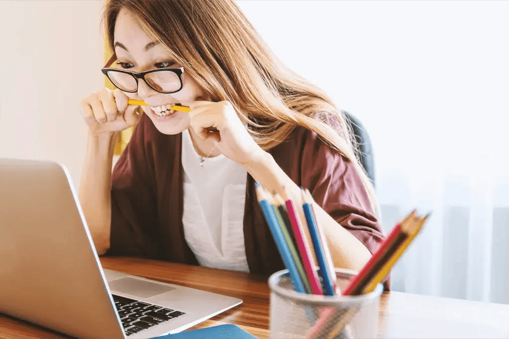 Vrouw achter laptop met bril en potloden