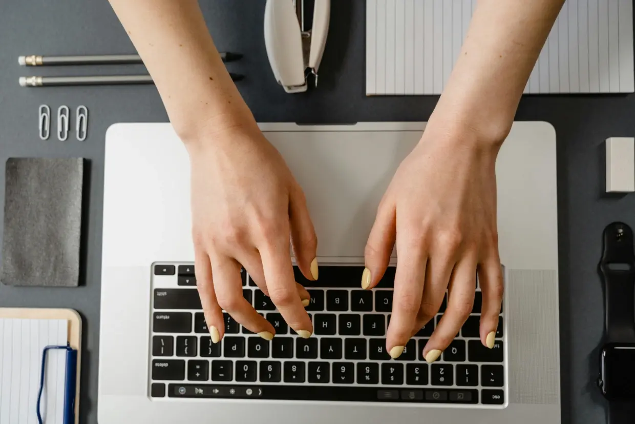 foto van boven gezien waarop iemand op een toetsenbord van een laptop typt